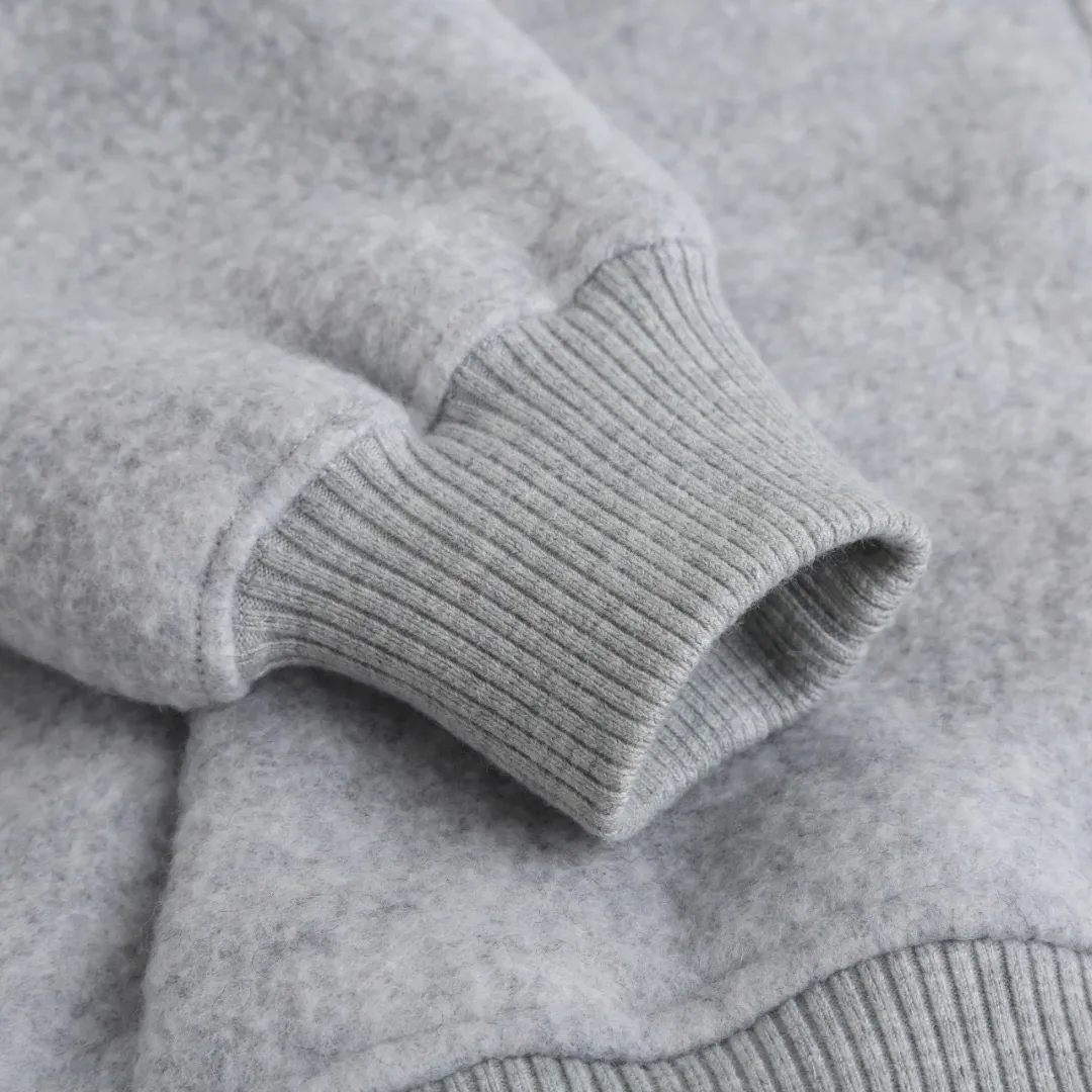 P780 Canada Goose Wool Fleece Hooded Jacket (Light Gray) The fabric is made of wool fleece fabric, which is mainly made of wool and mixed with a very small amount of spandex and polyester fiber. Wool is a core natural ingredient that provides unparalleled temperature regulation, antibacterial and anti-odor properties and a skin-friendly feel. The feeding of a small amount of spandex gives the fabric a certain degree of four-way elasticity, making it non-restrictive during daily activities. As the basis of fleece's structure, polyester fiber enhances the fabric's durability, wrinkle resistance and quick-drying properties. It contributes to the loft of the fleece and provides functions such as trapping air. The sleeves and hem are closed with 2×2 ribbing. Its strong elasticity can closely fit wrists and waists of different thicknesses, forming an effective 'seal' to prevent cold wind from blowing back. It can still maintain its original shape after repeated stretching and use, and is not easy to loose and deform. And the ribbed cuffs can convey a sense of design and enhance the visual beauty. The combination of hood design and elastic buckle improves warmth and windproof performance when worn. Size:S-M-L-XL